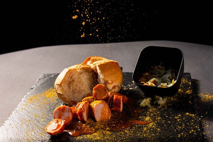 Currywurst mit Currysauce, Currypulver, Brötchen, Röstzwiebeln und Essiggurken